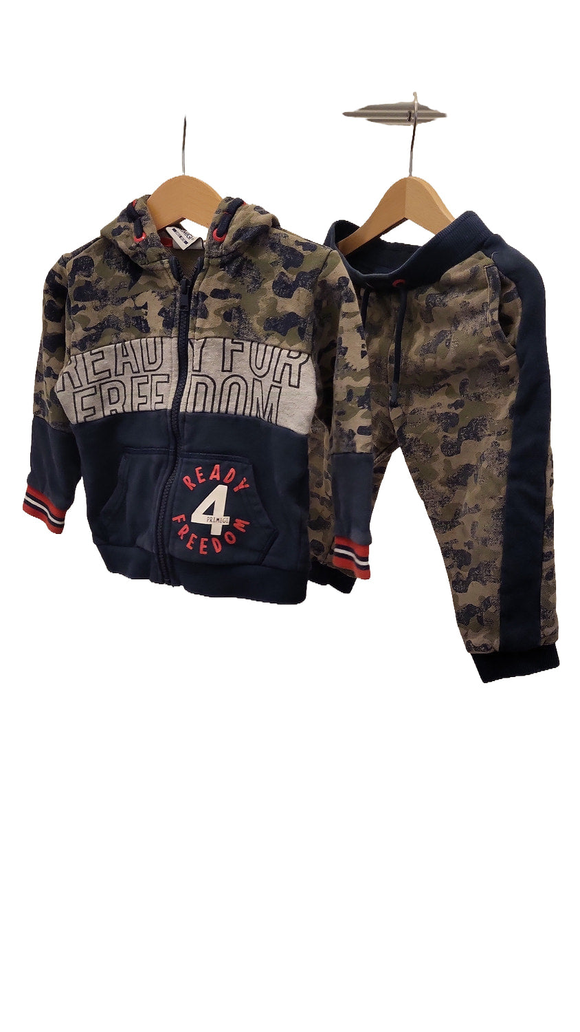 Both pieces of the camouflage tracksuit hang side by side on hangers: a zip-up hooded jacket with navy lower panels and 'Ready for Freedom' lettering, and matching joggers.