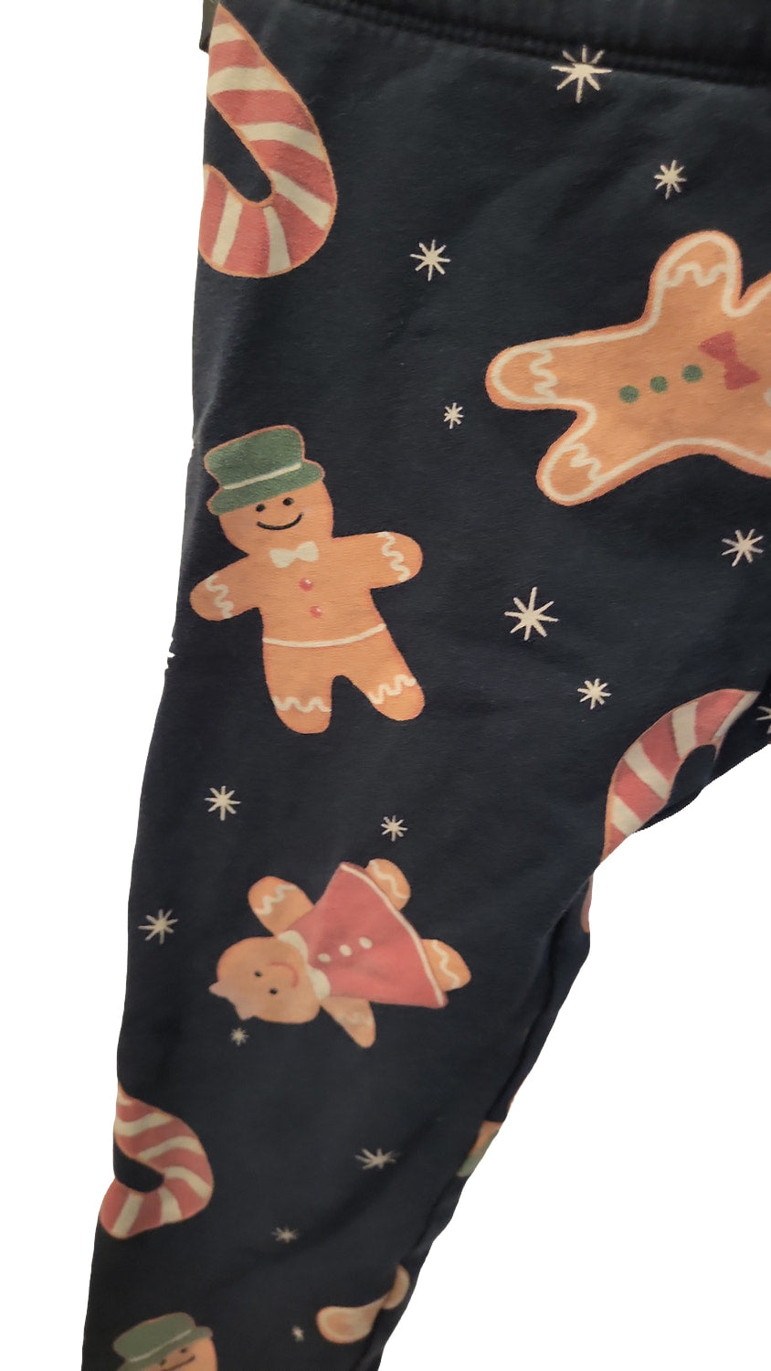 Close-up of the leg of the navy leggings showing gingerbread men with icing details and candy canes on the fabric.