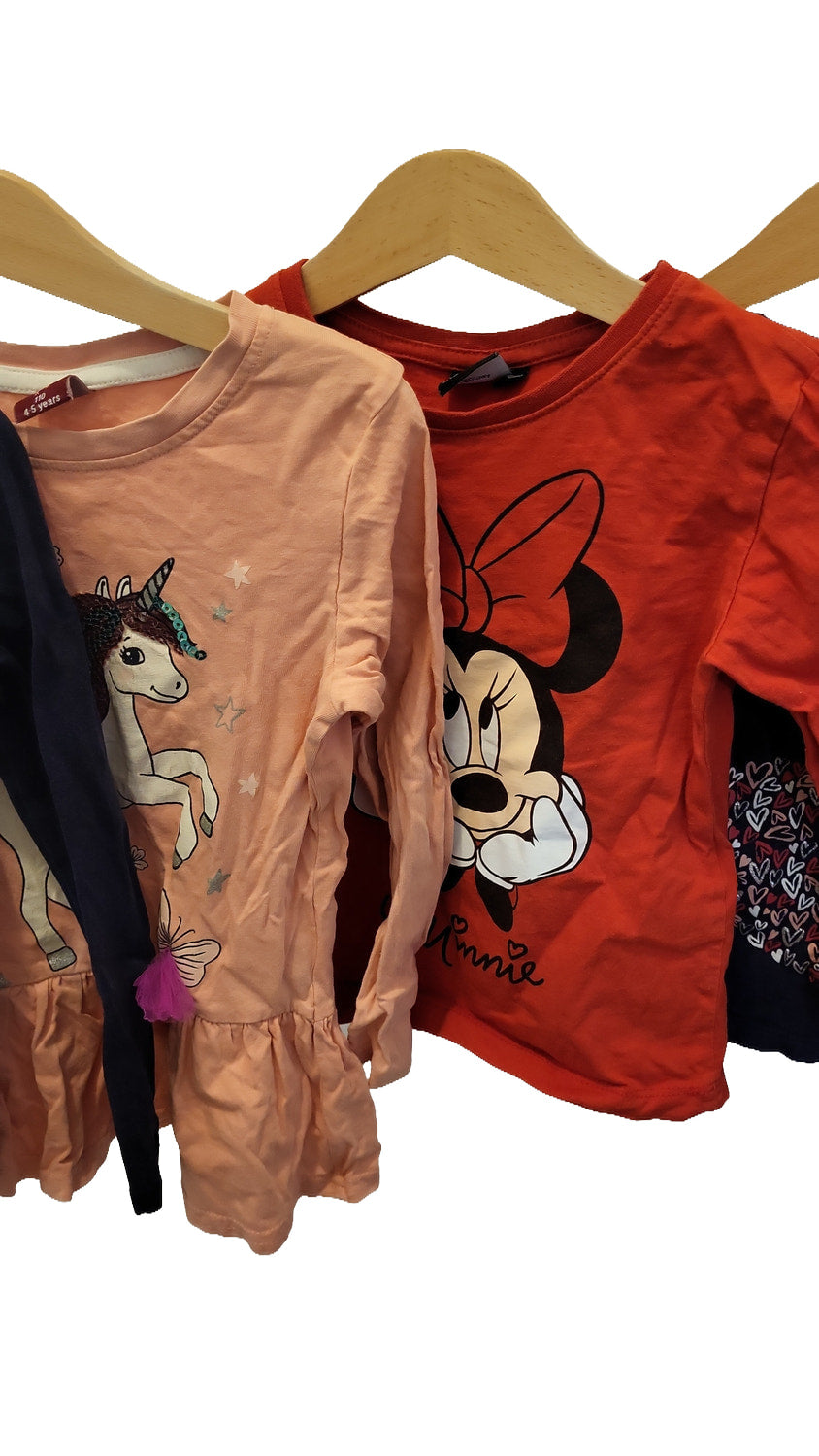 Close-up of the peach top with a unicorn, stars and a pink tassel on the ruffled hem, next to the red top with a Minnie Mouse print and the word 'Minnie'.